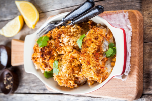 Cabillaud Aux Herbes or herb-crusted cod presented nicely in an oven tray with cutlery and lemon slices
