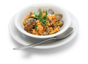 Neatly organised in a bowl, Fregola with clams and a metal spoon