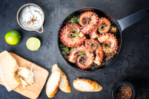 Grilled squid in a bowl with limes, bread, and aioli