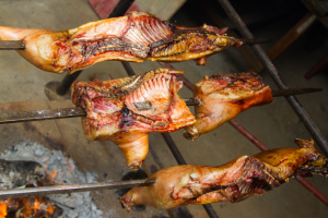 Pig meat on three skewers cooking