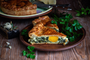 Torta Pasqualina on a plate with salad and herbs