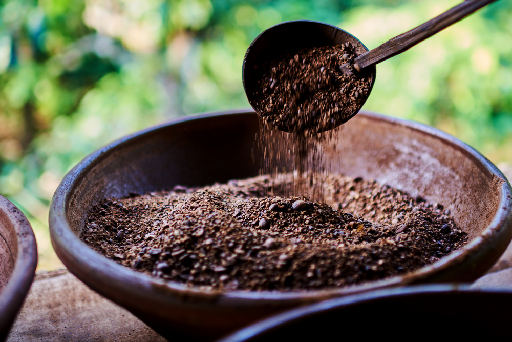 Kopi Luwak Coffee seeds in a bowl with a ladel scooping some out. Some seeds dropping back into the bowl.