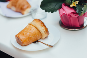 A baba al rum cake on a white plate with a spoon.