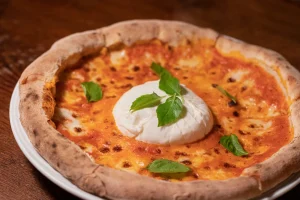 Thick dough burrata and truffle pizza with basil leaves.