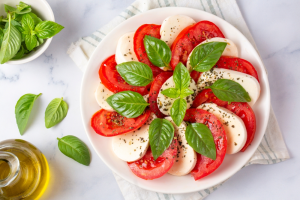 A white dish with mozzarella and tomato slices with herbs and basil.