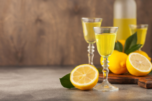 Two glasses of limoncello with a half lemon slice and two lemons.