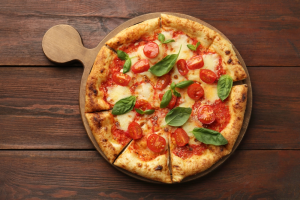 A margherita pizza on a wooden pizza server.