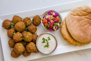 Falafel on white plate next to pita bread.
