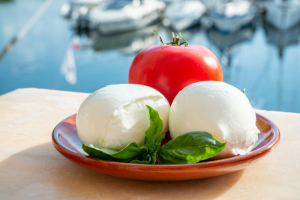 Tomato and two mozzarella balls on a red plate.