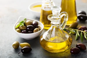 Jug of oil next to bowl of black and green olives.