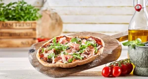A prosciutto and rocket pizza on a chopping board.