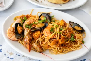 Seafood spaghetti with mussels and prawns in a white dish.